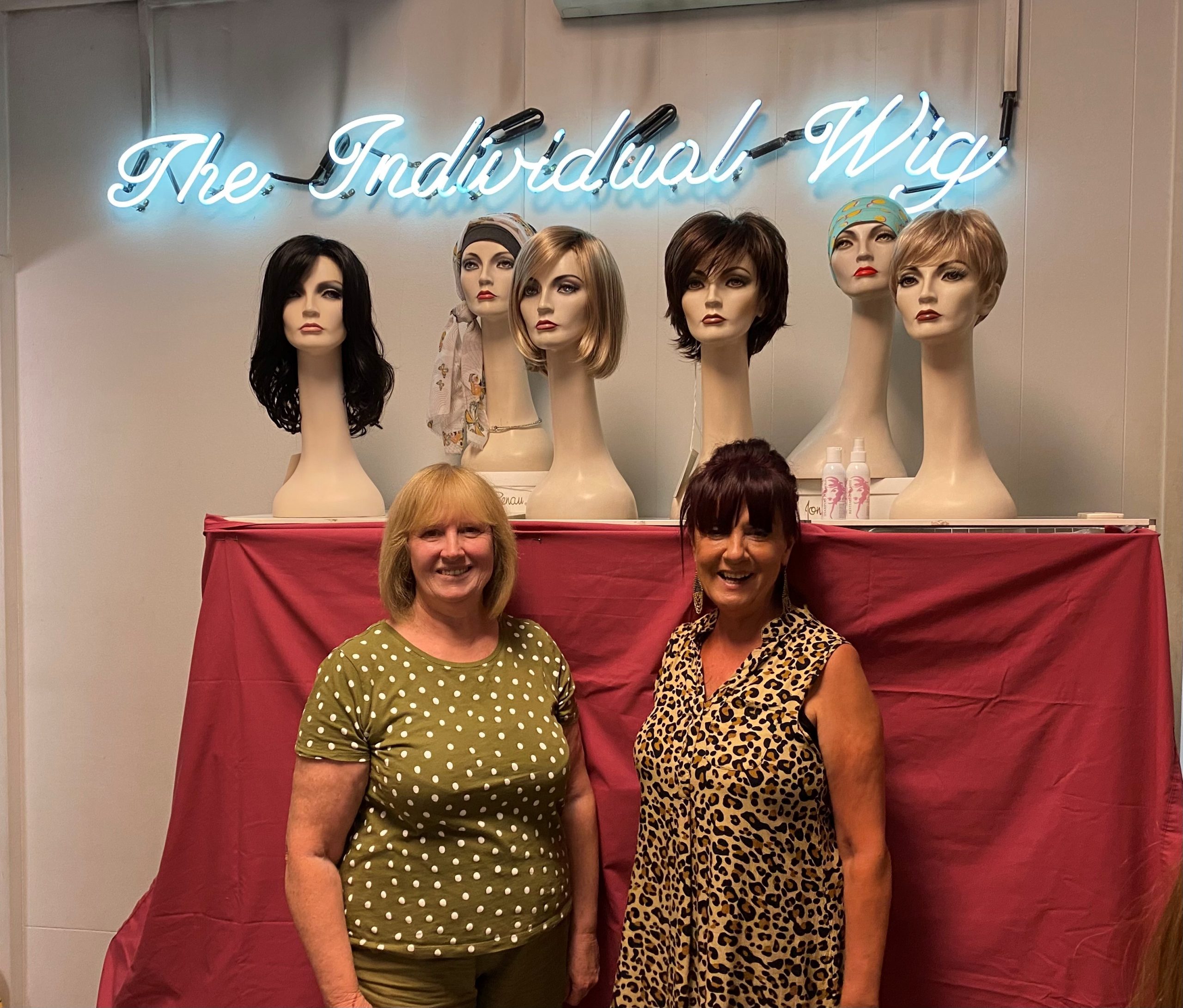 The team at The Individual Wig standing in front of some wigs displayed on mannequins