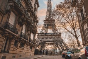 The Eiffel Tower shot from a low angle with Parisian street scape in the foreground