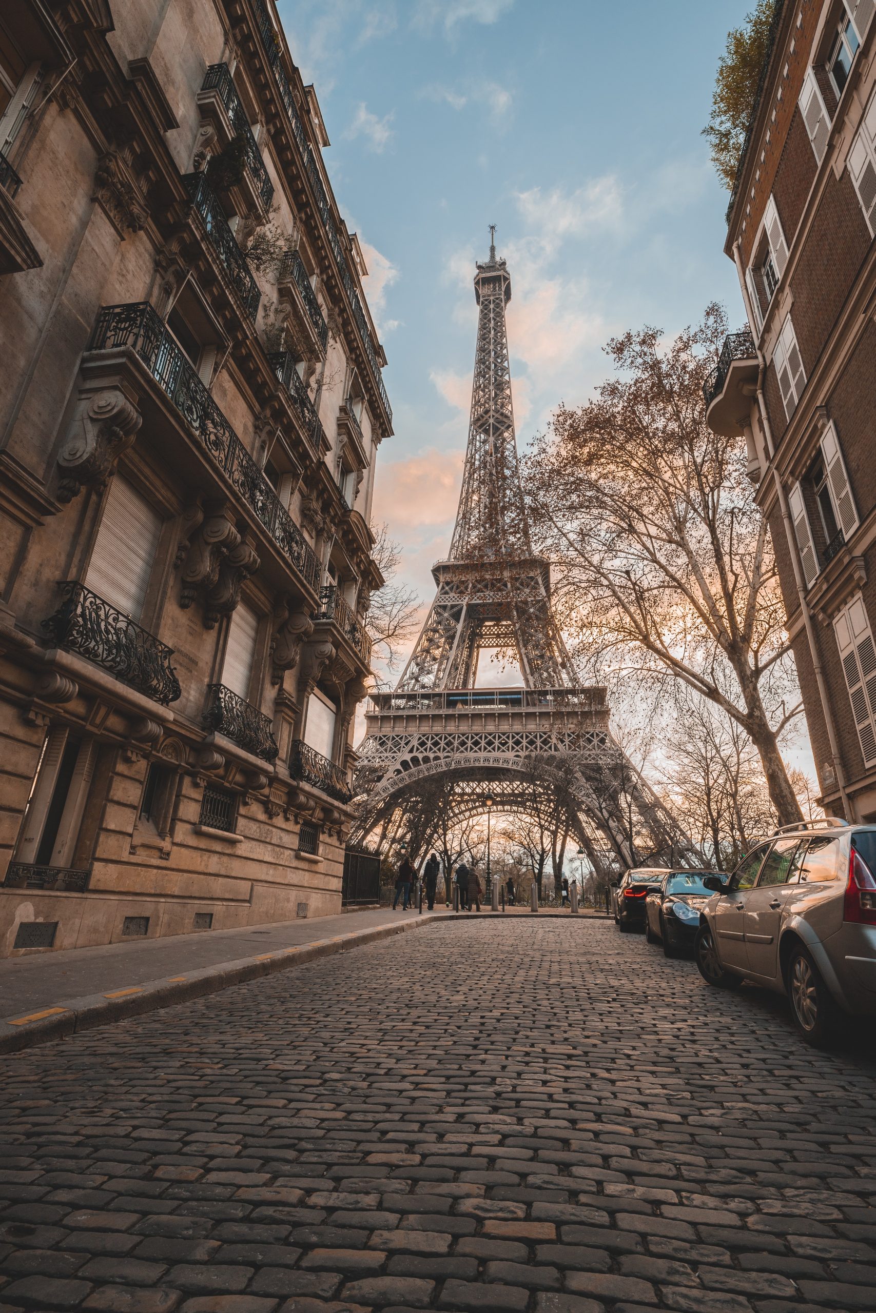 The Eiffel Tower shot from a low angle with Parisian street scape in the foreground