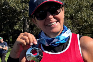 Sydney Marathon 2025 runner Laura Garbo pictured in her Team Arrow running singlet, holding her finisher's medal
